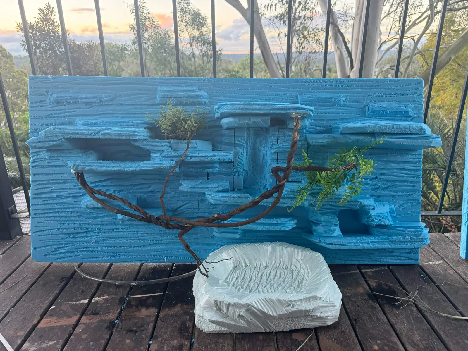 Four-foot enclosure backdrop taking shape in bright blue foam with branches and planting pockets